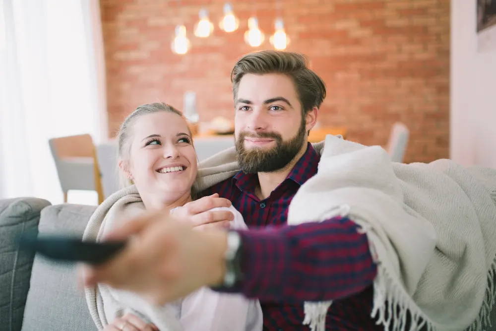 Un couple regarde la télévision ensemble avec l'abonnement annuel IPTV sur le canapé