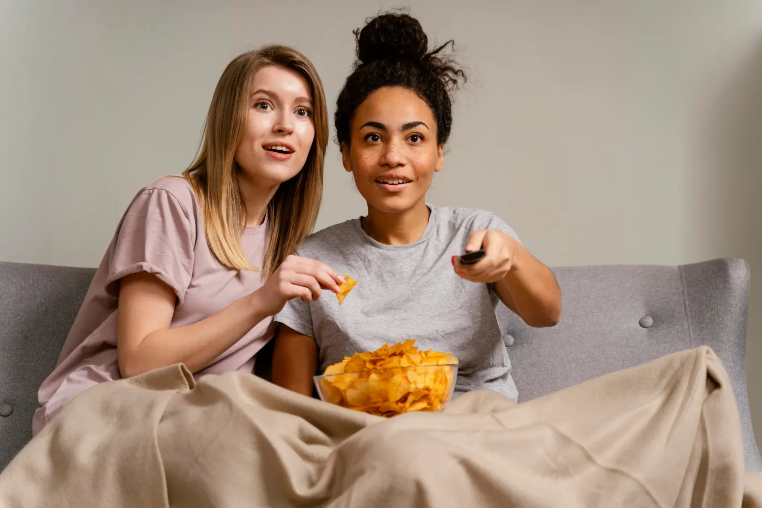 Deux femmes regardent la télévision sur le canapé avec des chips