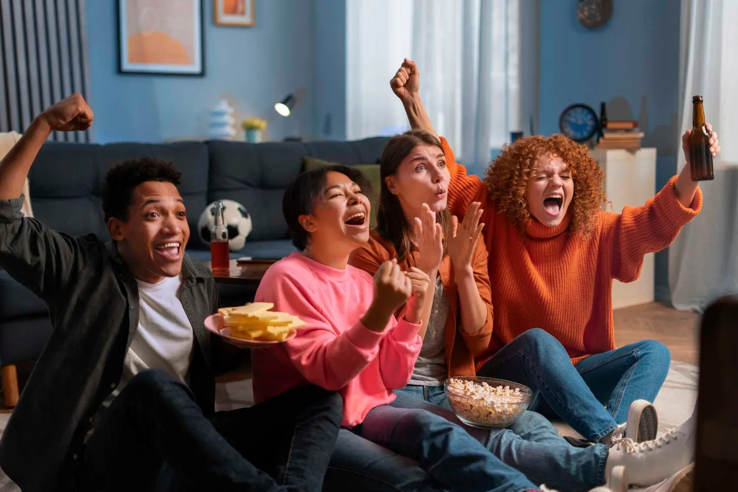 Des amis célèbrent ensemble pendant un match de football en direct à la maison